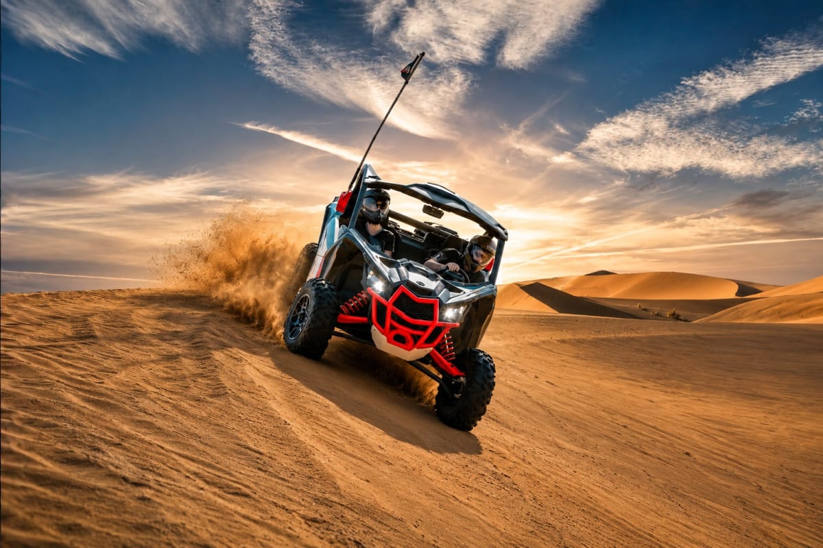 Two riders in a Can-Am Maverick buggy kicking up dust while driving across golden sand dunes in the desert (3)