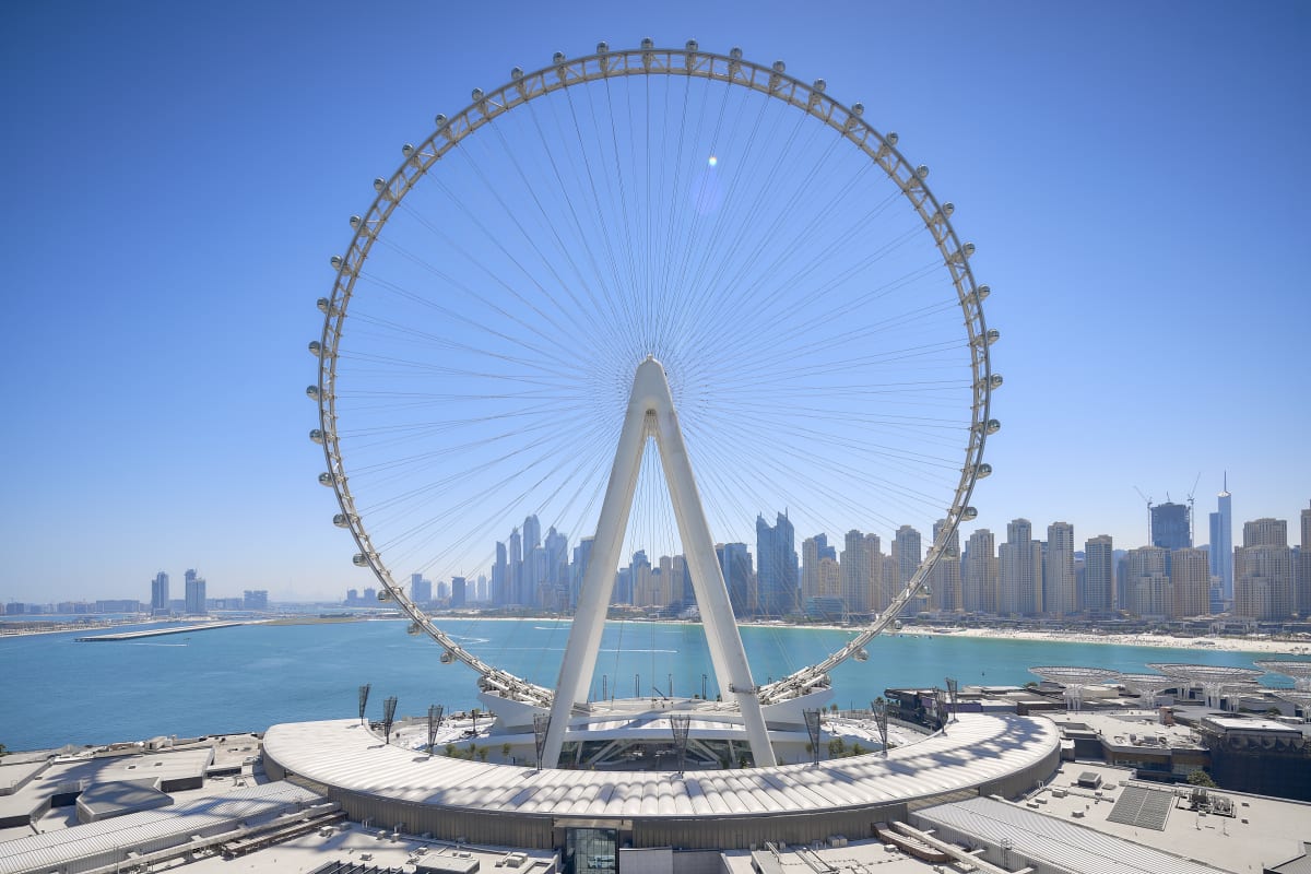 Ain Dubai observation wheel with white central pillar and cable supports overlooking Dubai coastline and turquoise water