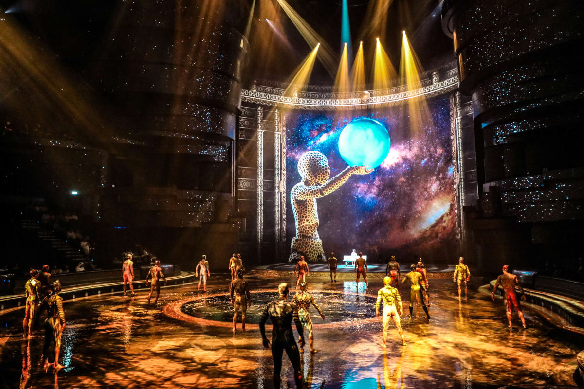 Futuristic circus performance inside La Perle theater with acrobats, illuminated wire sphere prop, and blue stage lighting (5)