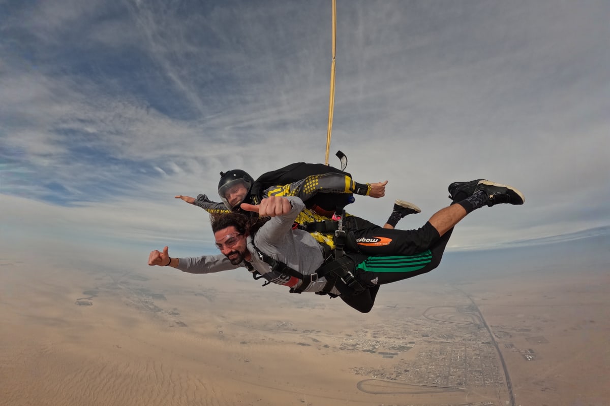 Skydiver in freefall above Palm Jumeirah with tandem instructor, showing Dubai's iconic palm-shaped islands and turquoise water (2)