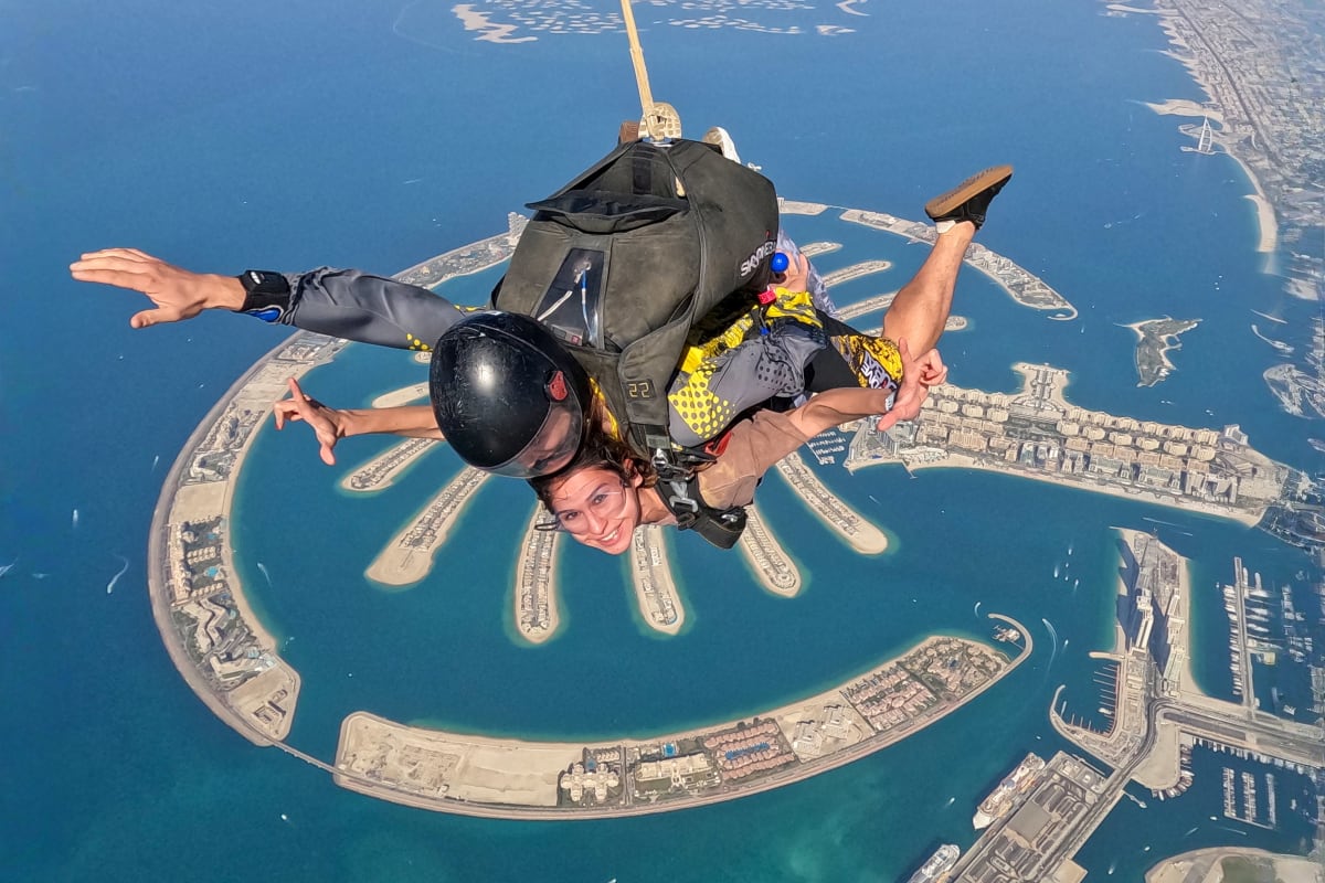 Skydiver in freefall above Palm Jumeirah with tandem instructor, showing Dubai's iconic palm-shaped islands and turquoise water (3)