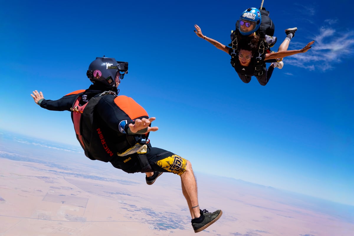 Skydiver in freefall above Palm Jumeirah with tandem instructor, showing Dubai's iconic palm-shaped islands and turquoise water (4)